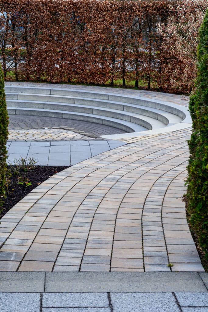 Curved brick pathway leading to a sunken seating area in Coesfeld garden.